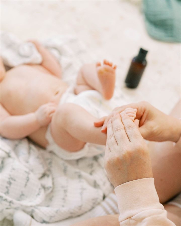 Les mains d'une praticienne massent les pieds d'un nouveau-né