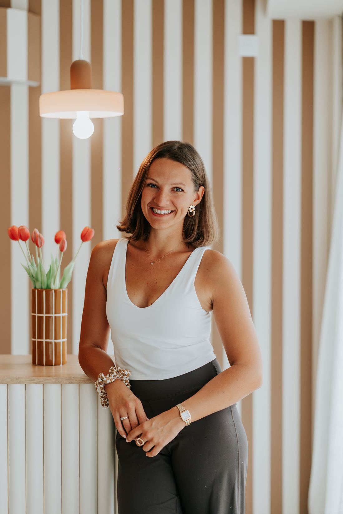 Constance, fondatrice de PAUSE studio, souriante devant le comptoir d'accueil et son bouquet de tulipes