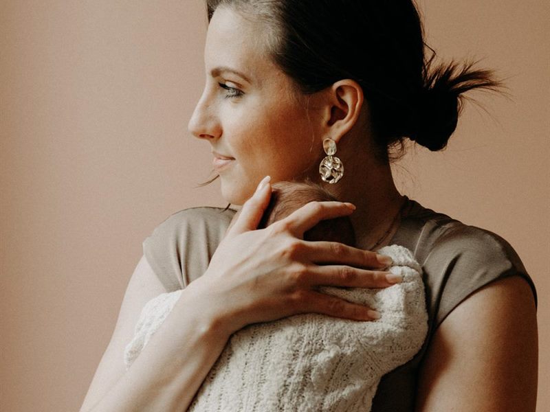 Une mère tient son nouveau-né contre elle, dans une lumière douce