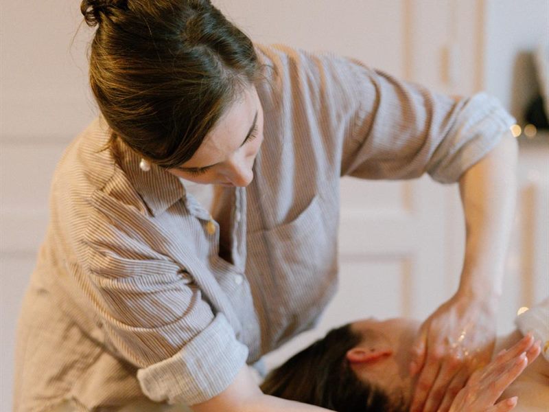 Une praticienne réalise un soin sur une femme allongée sur la table de massage